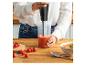Vrouw mixt tomatensoep met een staafmixer, met verse tomaten en zout.