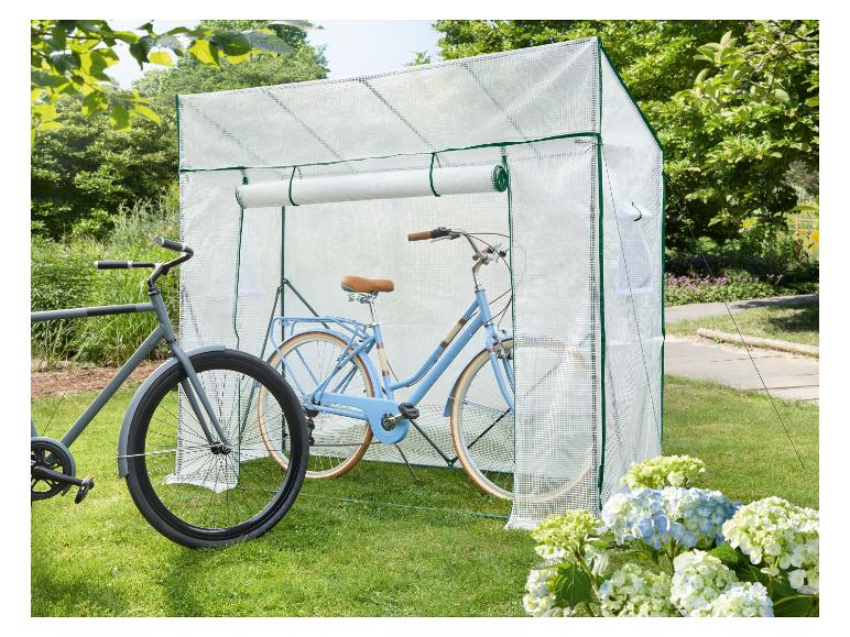 Twee fietsen, één lichtblauw en één grijs, opgeborgen in een transparante fietsenstalling op een gazon.