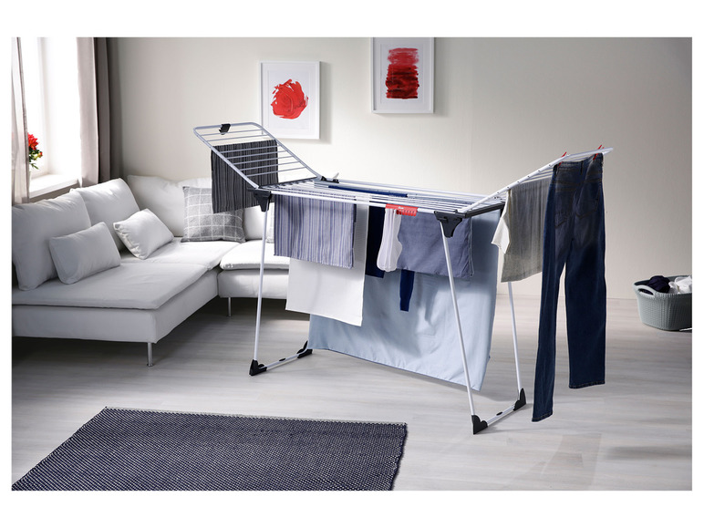 Een wit droogrek met kleding en handdoeken in een woonkamer.