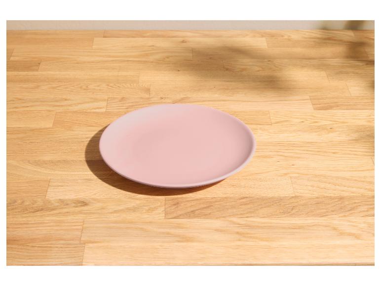 Roze bord op een lichte houten tafel met zonlicht en schaduwen.