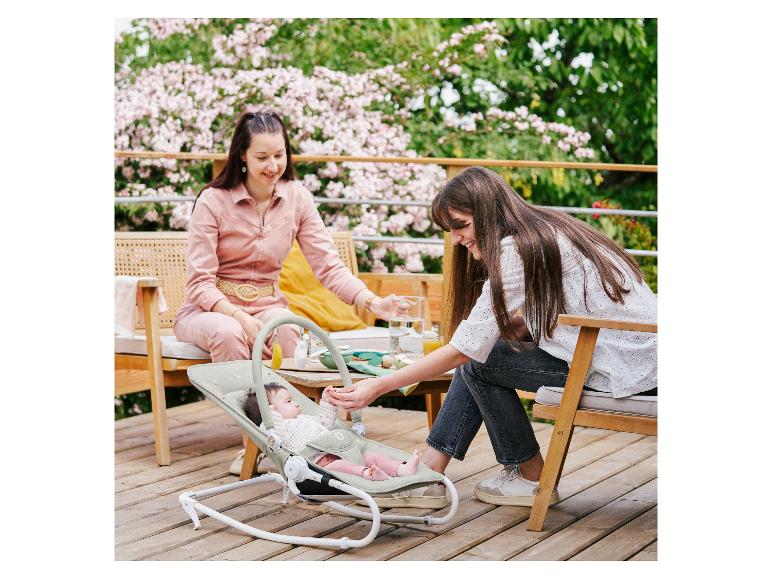 Twee vrouwen verzorgen een baby in een Chicco wipstoel op een terras.