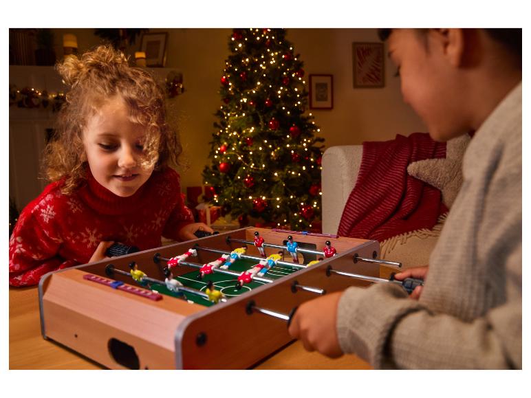 Kinderen spelen tafelvoetbal bij een kerstboom