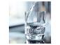 Water wordt in een glas geschonken, met reflecties op het oppervlak.