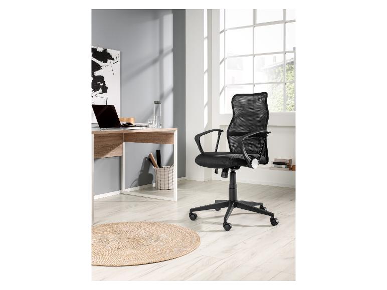 Bureau, zwarte mesh bureaustoel en rond tapijt.