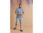 Man in een blauwe T-shirt en grijze shorts met sandalen.