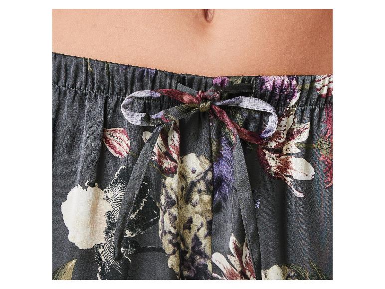 Close-up van het middel van een persoon die een pyjamabroek met bloemenprint en trekkoord draagt.