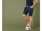 Man draagt blauwe shorts en witte sneakers.