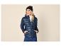 Vrouw in een marineblauwe pufferjas, witte coltrui, zwarte muts en blauwe jeans.