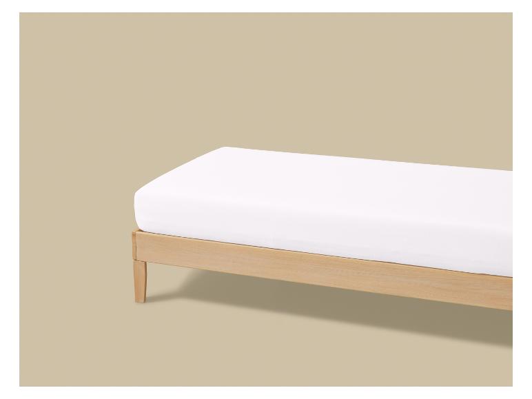 Houten bed met een wit matras op een beige achtergrond.