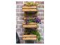Houten wandplantenbak met paarse bloemen en groene planten aan een bakstenen muur.