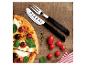 Pizzaset met mes en vork, naast pizza met tomaten en olijven op een houten ondergrond.