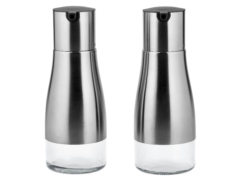 Twee olie- of azijndispensers van roestvrij staal en glas.