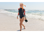 Vrouw in shirt met lange mouwen, bikinibroekje en snorkelmasker loopt op het strand.