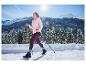Vrouw in CRIVIT thermo softshell jas en paarse legging wandelt in besneeuwd berglandschap.
