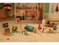Poppenhuis met miniatuurfamiliefiguren, meubels en een tv die nieuws toont.