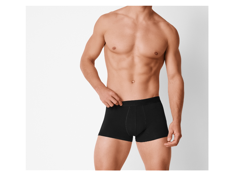 Een man toont zwarte boxershorts.