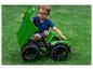 Jonge jongen in blauw shirt en bril speelt met groene speelgoedtruck op gras.