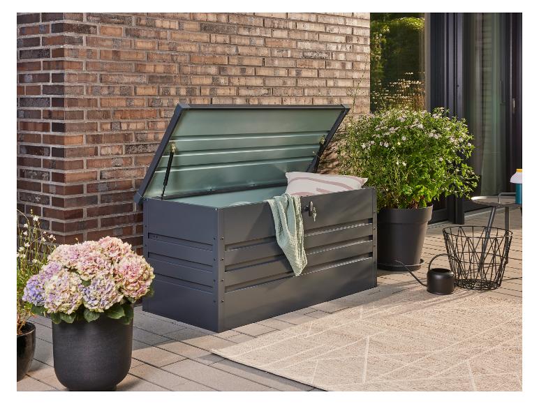 Donkergrijze tuinopbergbox met open deksel, naast potplanten op een terras.