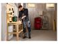 Een man in een PARKSIDE PERFORMANCE® werkgilet boort in een houten tafel in een werkplaats.