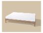 Houten bed met wit matras op beige achtergrond.