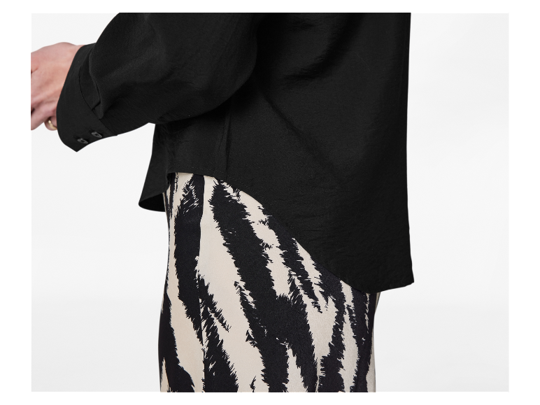 Zwart overhemd met lange mouwen en zwart-witte zebrastrepen rok.