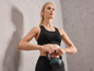 Een vrouw in sportkleding met een zwarte kettlebell.