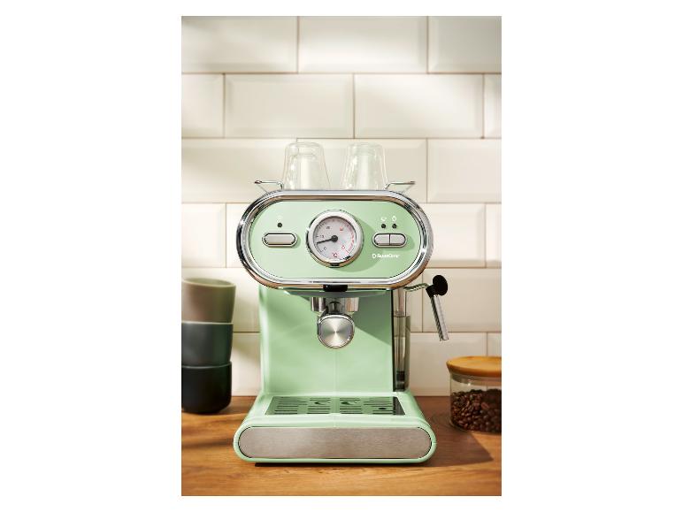 Mintgroen espressomachine met glazen kopjes op een houten aanrecht.