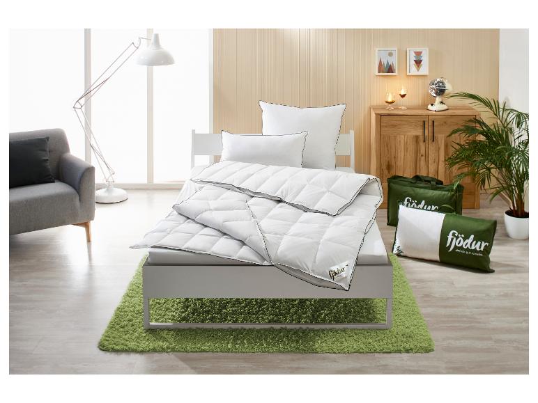 Wit Fjödur dekbed en kussens op een bed met groen vloerkleed in een lichte slaapkamer.