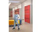 Jongen in lichtblauw trainingsjack en bijpassende broek in een schoolgang met rode kluisjes.