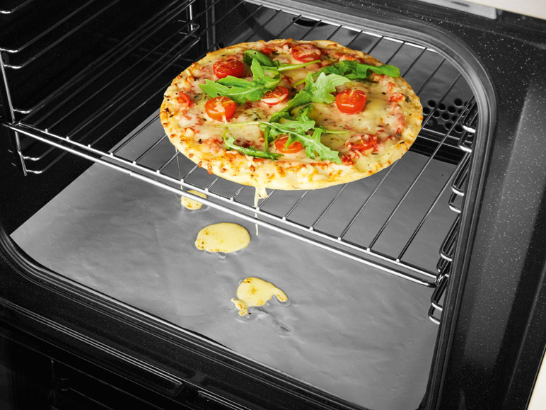 Een pizza met mozzarella, tomaat en rucola op een bakplaat in een oven.
