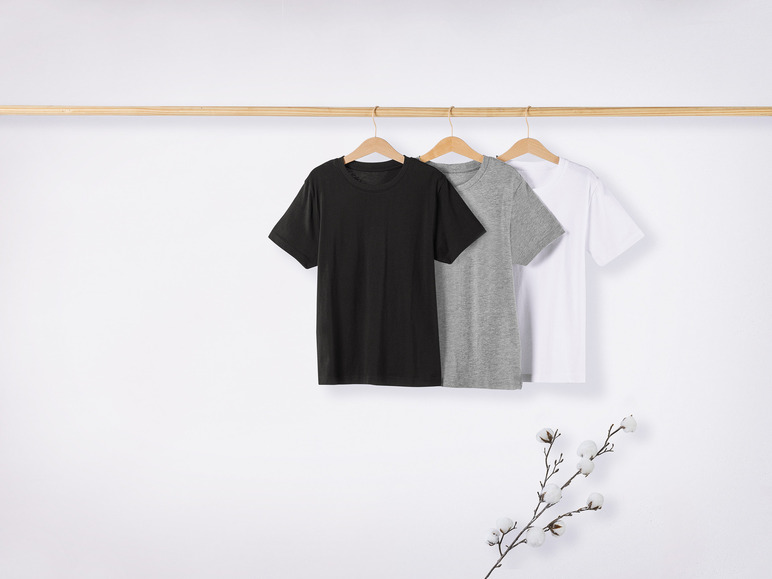 Zwarte, grijze en witte T-shirts op een houten hanger.
