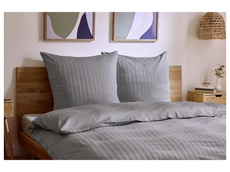 Grijs gestreept beddengoed op een houten bed, met een nachtkastje en wanddecoratie.