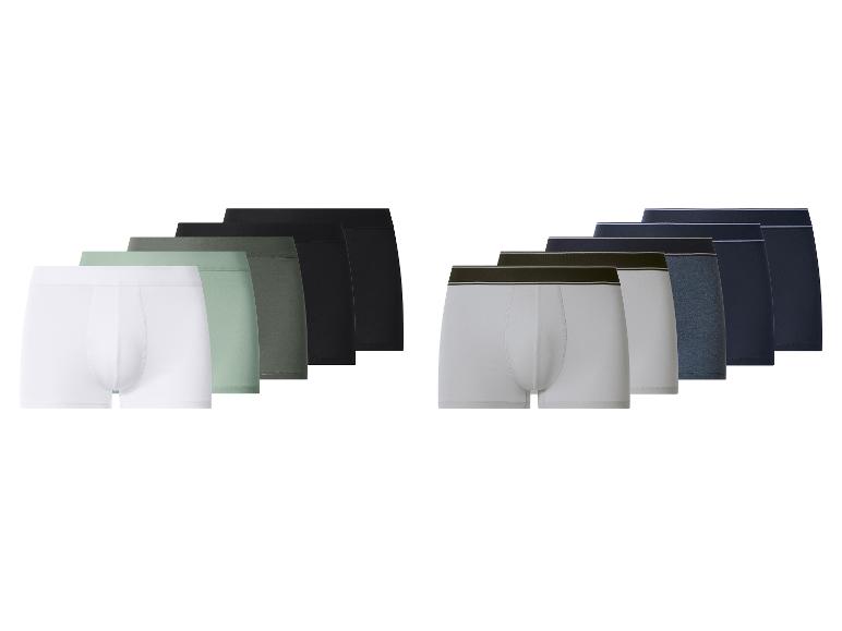 Twee sets herenboxers in diverse effen kleuren, waaronder wit, groen, zwart, grijs en blauw.