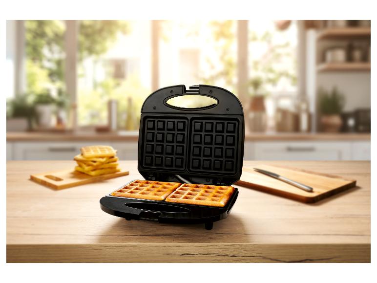 Versgebakken wafels en een wafelmaker op een aanrecht.