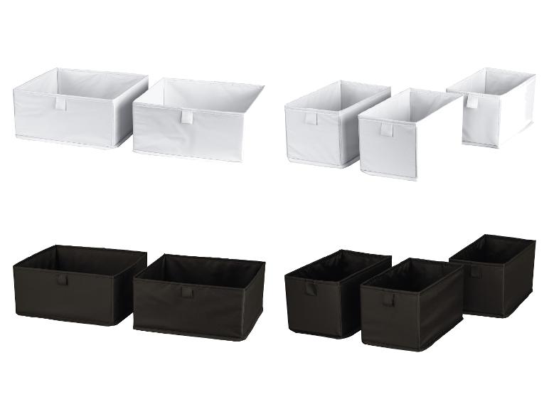 Twee sets witte en zwarte stoffen opbergdozen in diverse maten.