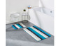 Badkamer met bad, toilet en twee badmatten met blauwe strepen.