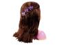 Pop met lang, bruin haar, gestyled met een vlecht en paarse kroonvormige haarclips.