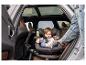 Een baby zit in een draaibare autostoel achterin een auto.