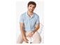 Man in lichtblauw poloshirt en beige broek, zittend op een metalen stoel.
