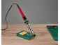 Soldeerbout met houder en spons, en siliconenmat op een houten tafel.