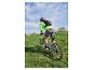 Fietser met rugzak en groen fietsshirt op een mountainbike in een grasveld.
