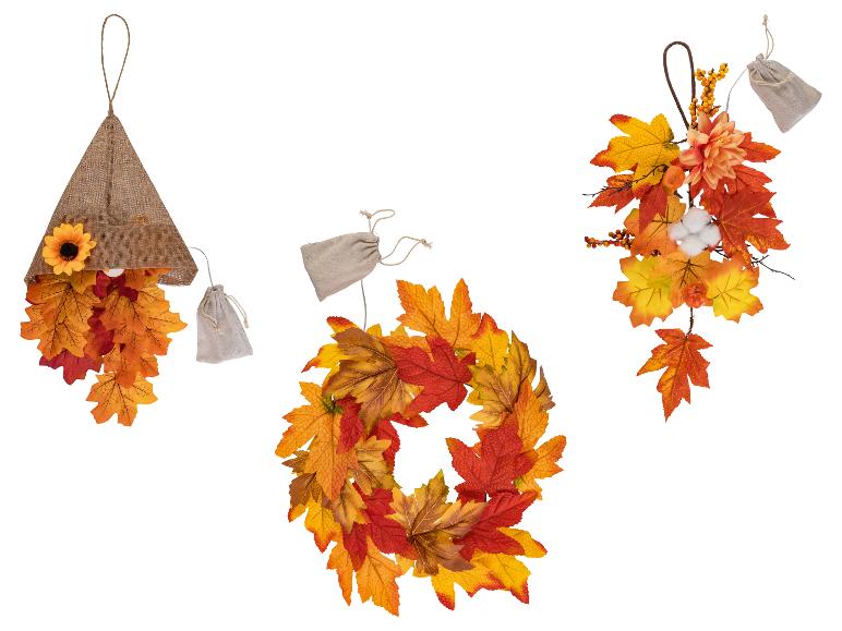Herfstdecoraties met esdoornbladeren, zonnebloem en bessen, inclusief een krans en hangende ornamenten.