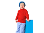 Jongen in rode coltrui met kompas en blauwe broek, leunend op een blauw blok.