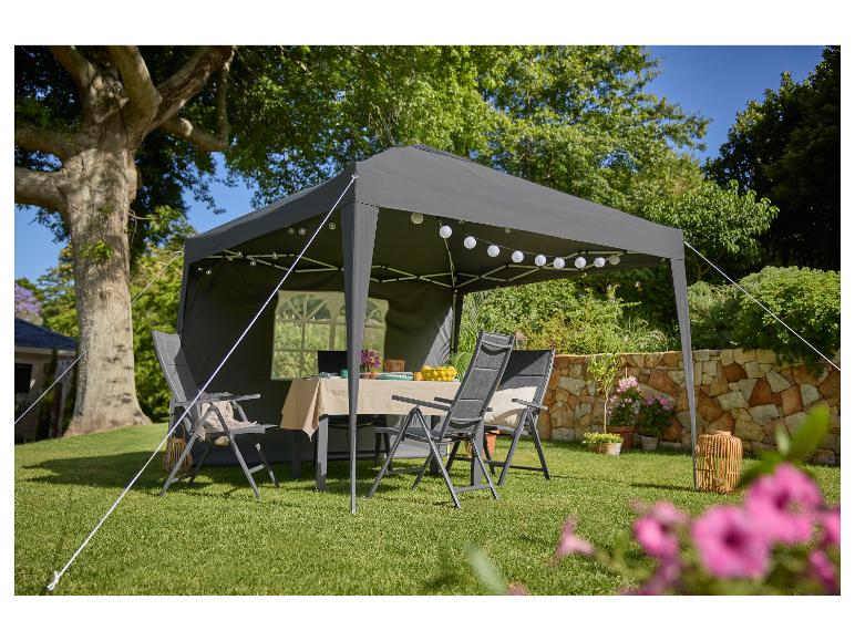 Grijze partytent met meubels en decoraties in een tuin.