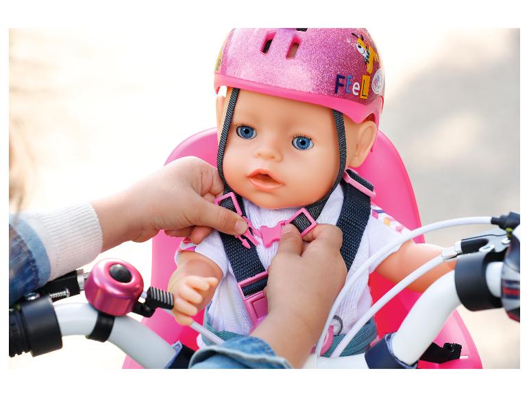 Kinderhanden maken een pop met roze helm vast in een fietszitje.