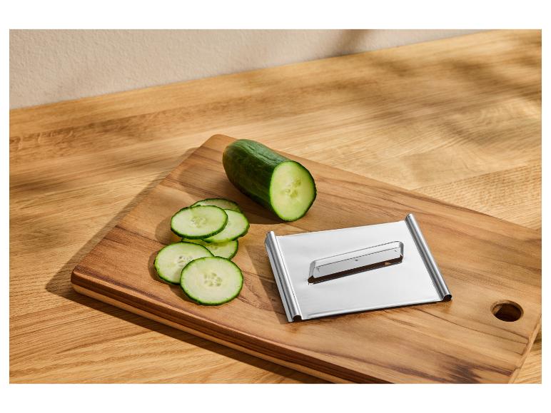 Gesneden komkommer en keukenmandoline op een houten snijplank.
