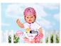 BABY born pop met roze helm en fiets, met een wit hek op de achtergrond.