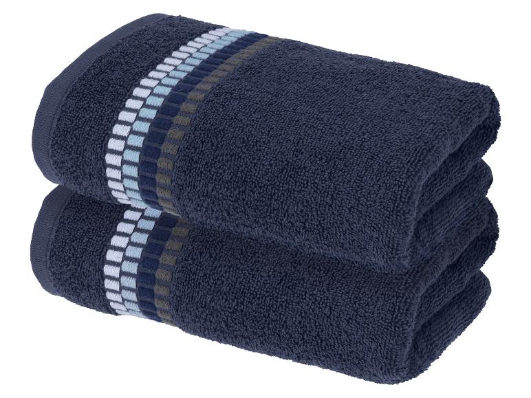 Twee gevouwen donkerblauwe handdoeken met een decoratief gestreept patroon