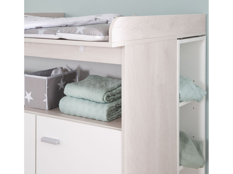 Een commode met een commodemat, lade en open vakken.