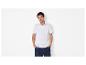 Man in wit poloshirt en marineblauwe korte broek, met handen in zakken.
